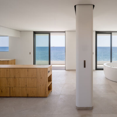 Innenraum von the ONE Ibiza mit freistehender Badewanne, Holzmöbel und Meerblick.