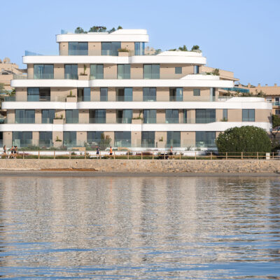 Vista frontal de the ONE Ibiza desde el mar con el paseo marítimo en primer plano.