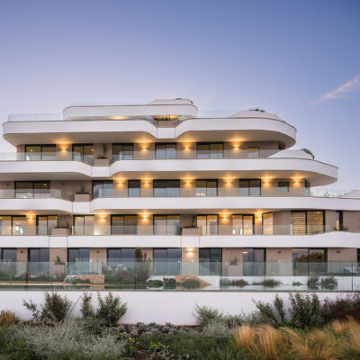 Fachada de the ONE Ibiza frente a la piscina con iluminación al anochecer.