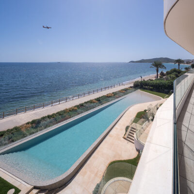 Piscina comunitaria y paseo marítimo vistos desde una terraza de the ONE Ibiza.
