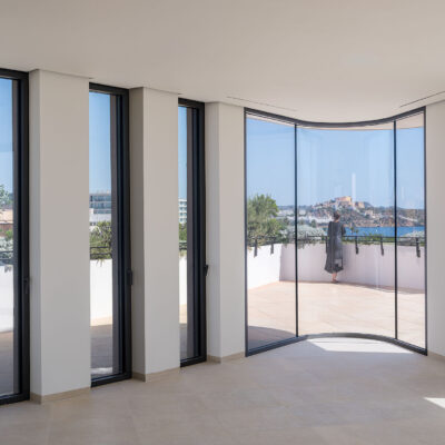 Interior de the ONE Ibiza con ventanal curvo y vistas a la terraza.